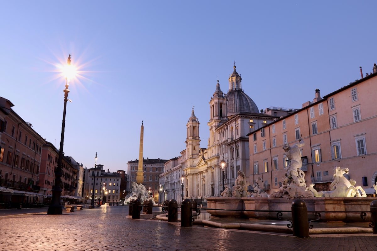 Piazza Navona a Roma deserta all'alba con l'obelisco e la fontana barocca