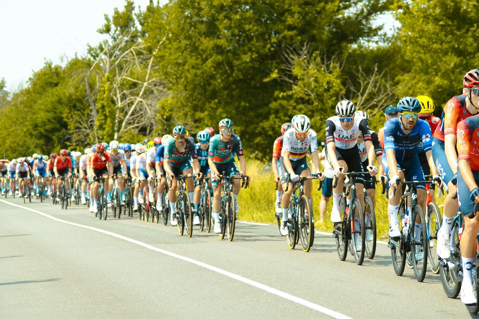 Gruppo di ciclisti professionisti in corsa, peloton compatto su strada