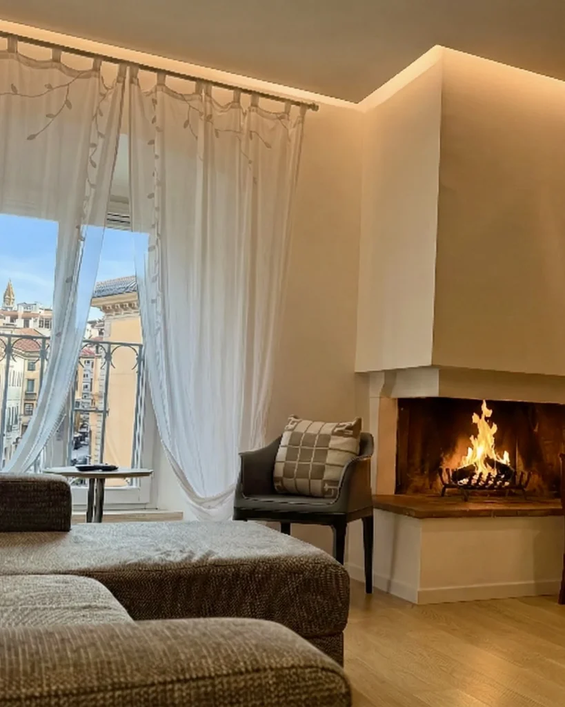 Soggiorno con camino acceso e grande finestra, Respiro, Assisi