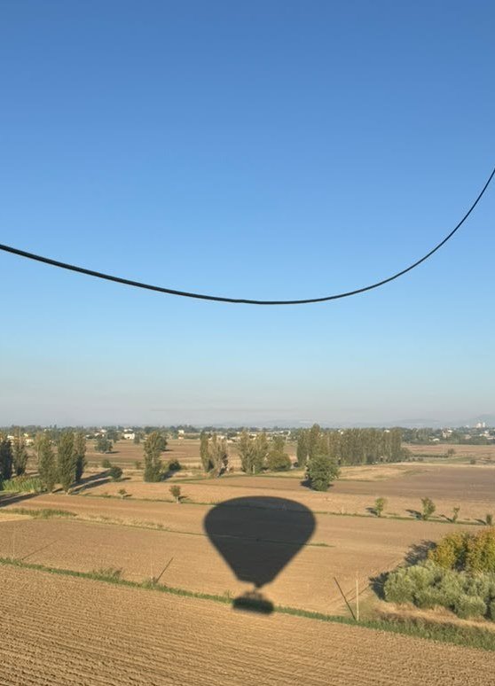 Ombra della mongolfiera sui campi della Valle Umbra, vista dal cesto in una mattina limpida